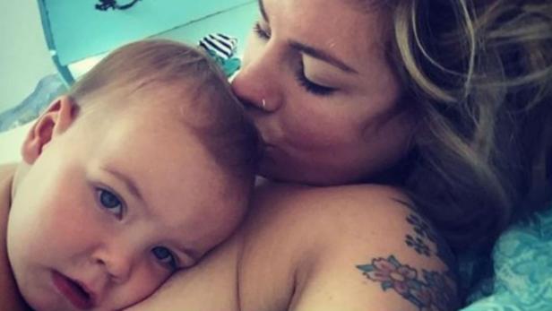 Eine Frau küsst ein Baby auf die Stirn.