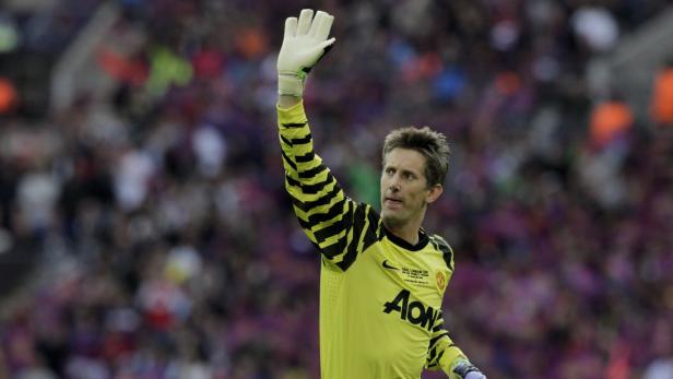 Ein Torwart in gelb-schwarzem Trikot winkt mit einem Handschuh in die Zuschauermenge.