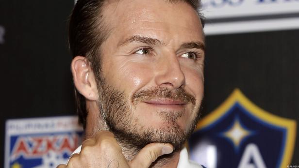 David Beckham mit Bart, die Hand ans Kinn gelegt.