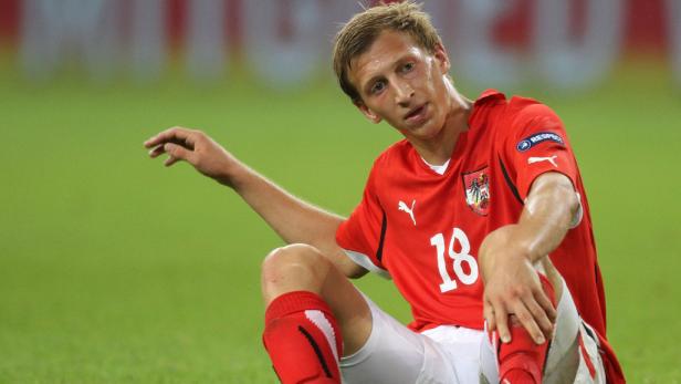 Ein österreichischer Fußballspieler sitzt erschöpft auf dem Rasen.