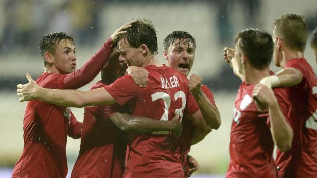 Eine Gruppe Fußballspieler in roten Trikots feiert ein Tor.