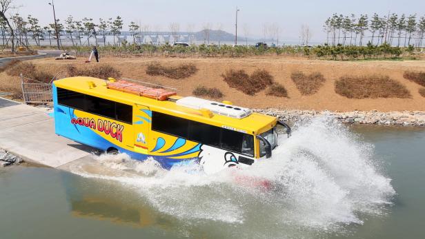 Ein gelb-blauer „Aqua Duck“-Bus fährt ins Wasser.