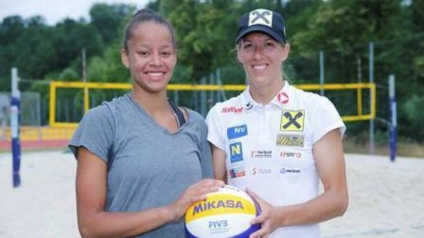 Zwei Beachvolleyballspielerinnen posieren mit einem Mikasa-Ball am Strand.