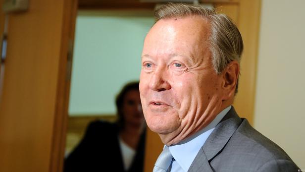 Ein älterer Mann in einem grauen Anzug schaut zur Seite.