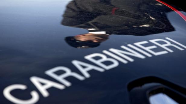 Die Aufschrift „Carabinieri“ auf einem dunklen Fahrzeug mit der Spiegelung einer Person.