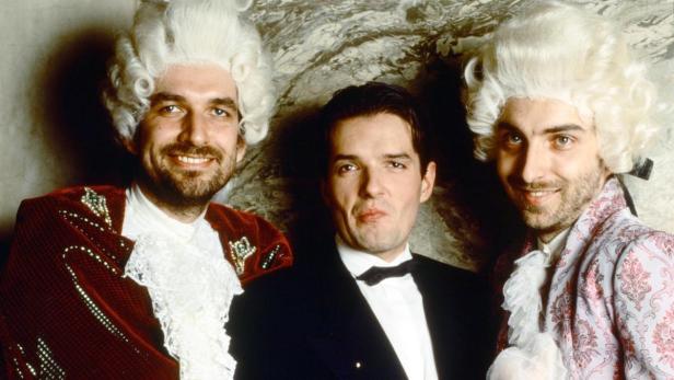 Drei Männer posieren in historischen Kostümen und Perücken für ein Foto.