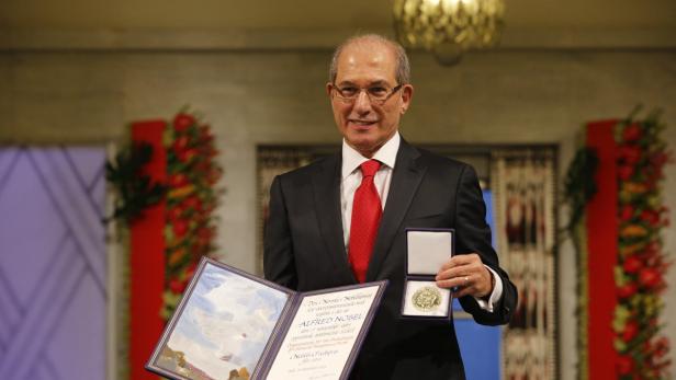 Mazen Darwish hält seine Nobelpreis-Urkunde und die Medaille.