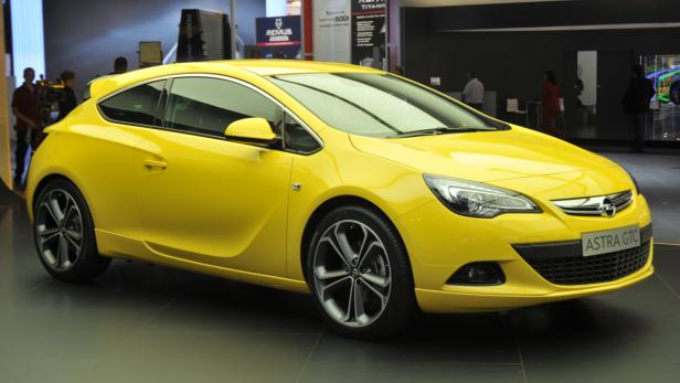 Ein gelber Opel Astra GTC steht in einem Ausstellungsraum.