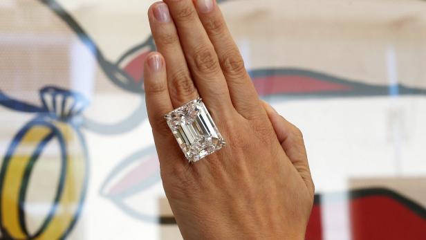 Ein großer Diamantring an der Hand einer Person.