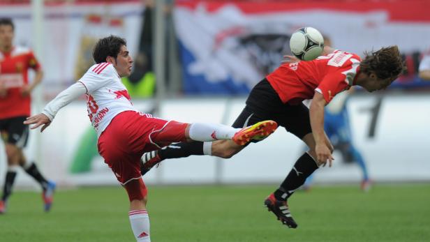 Zwei Fußballspieler kämpfen um den Ball während eines Spiels.