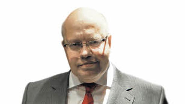 Ein Mann mit Brille, Anzug und roter Krawatte blickt in die Kamera.
