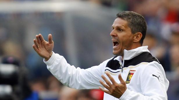 Ein Fußballtrainer gestikuliert aufgeregt am Spielfeldrand.