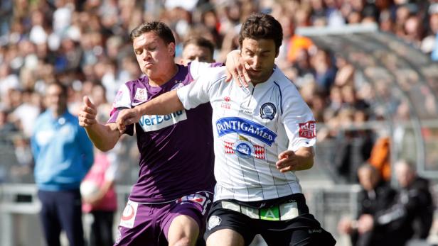 Zwei Fußballspieler kämpfen um den Ball während eines Spiels.