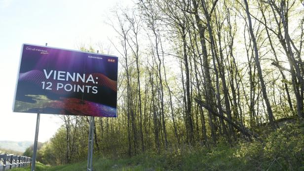 Eine Werbetafel mit der Aufschrift „Vienna: 12 Points“ steht am Straßenrand.