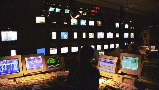 In einem Kontrollraum überwachen Personen zahlreiche Monitore.