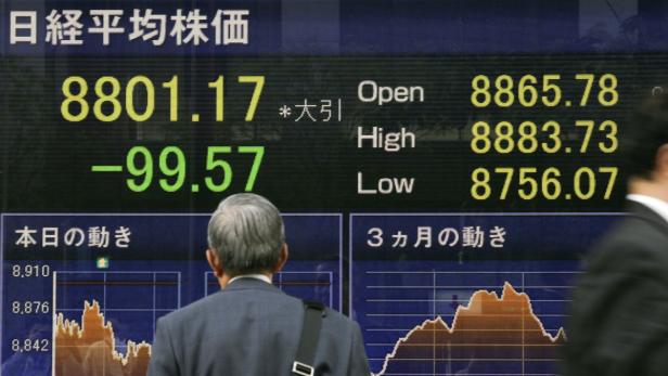 Ein Mann betrachtet eine Anzeigetafel mit dem Nikkei-Aktienindex.