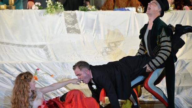 Der „Jedermann“ (Cornelius Obonya, Mitte) versucht sich an die Welt zu binden. Doch die Buhlschaft (Brigitte Hobmeier) ist schon fast geflohen, und der Tod (Peter Lohmeyer) naht verlässlich