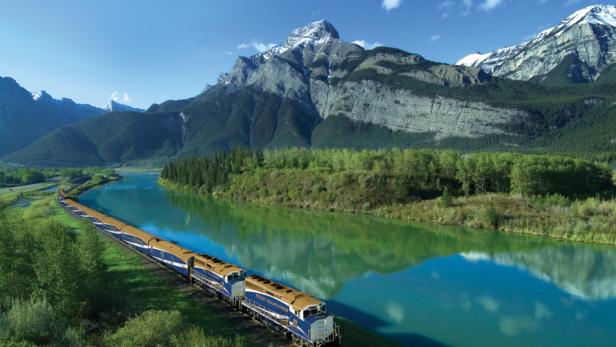 Der Rocky Mountaineer Zug fährt entlang eines Flusses in den Rocky Mountains.