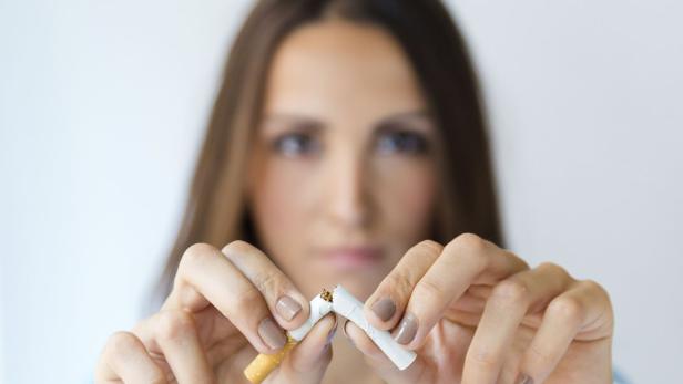 Eine Frau zerbricht eine Zigarette mit ihren Fingern. 
