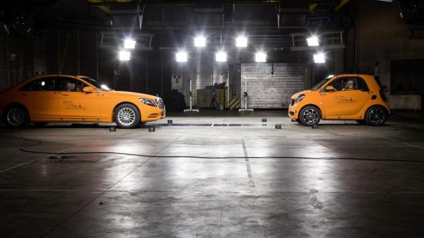 Ein Mercedes-Benz und ein Smart stehen sich in einer Crashtest-Anlage gegenüber.