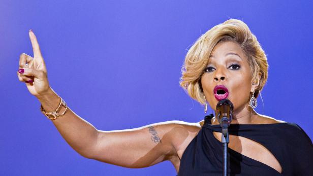 Mary J. Blige singt mit erhobenem Zeigefinger auf einer Bühne.