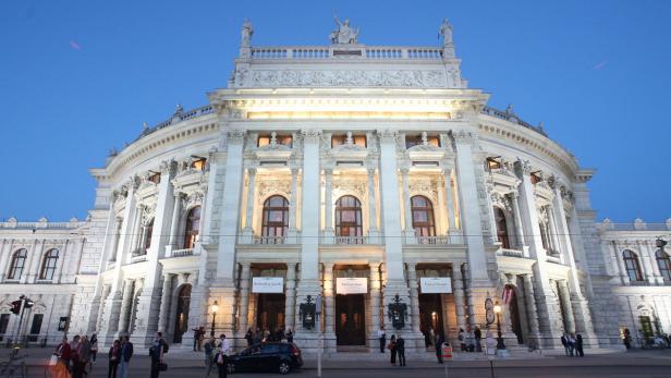 Die Wiener Staatsoper bei Dämmerung mit Menschen davor.