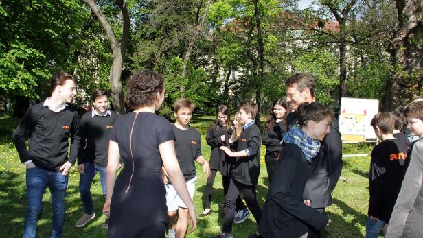 Eine Gruppe von Jugendlichen steht mit einem Mann in einem Park zusammen.