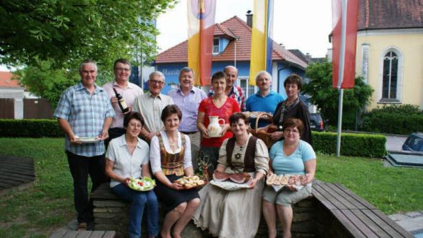 Eine Gruppe von Menschen posiert mit Speisen im Freien für ein Foto.