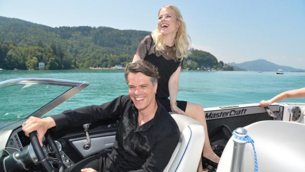Ein Mann und eine Frau lachen auf einem Motorboot auf einem See.