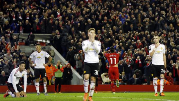 Enttäuschte Fußballspieler von Manchester United vor einer jubelnden Zuschauermenge.