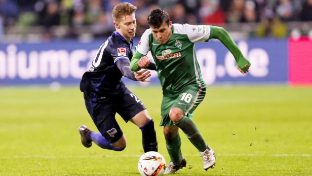 Zwei Fußballspieler kämpfen um den Ball auf dem Spielfeld.
