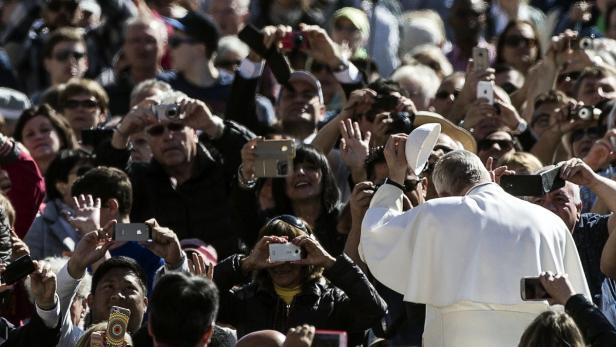 Papst Franziskus wird von einer Menschenmenge mit Kameras und Handys fotografiert.