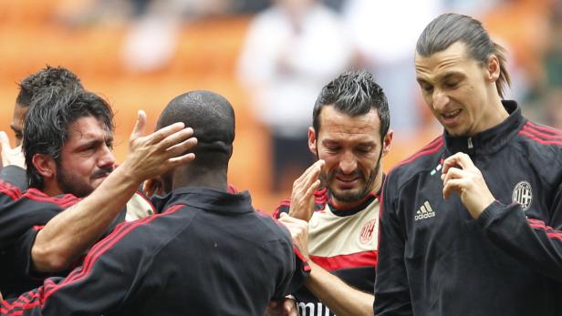 Mehrere Fußballspieler von AC Mailand umarmen sich auf dem Spielfeld.