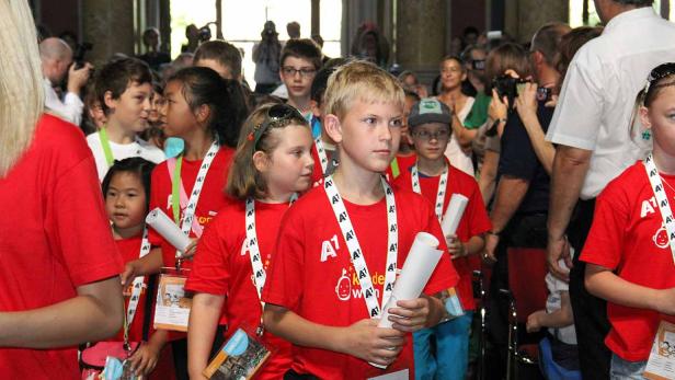 Eine Gruppe Kinder in roten T-Shirts mit A1-Logo steht in einem Raum.