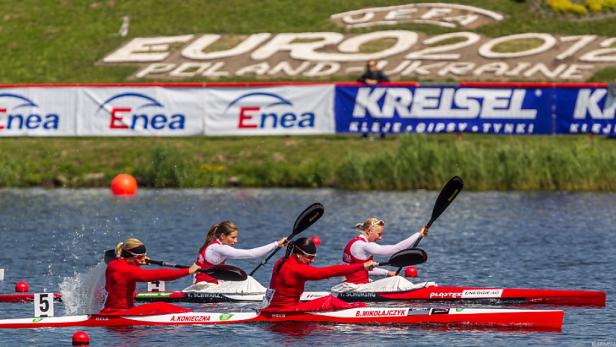 Drei Kanus mit Sportlerinnen bei einem Rennen auf dem Wasser.