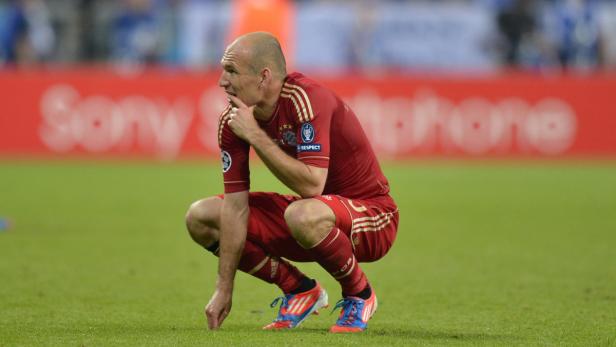 Arjen Robben hockt auf dem Rasen und blickt nachdenklich zur Seite.