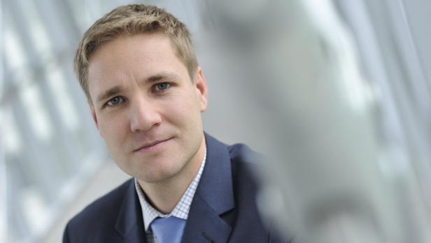 Ein Mann mit blonden Haaren und blauem Anzug blickt in die Kamera.