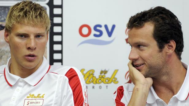 Zwei Männer in Sportkleidung sitzen vor einem OSV-Logo.
