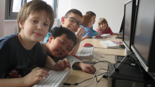 Eine Gruppe von Kindern sitzt an Computern in einem Klassenzimmer.