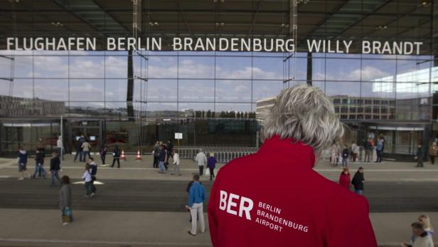 Eine Person steht vor dem Flughafen Berlin Brandenburg (BER).