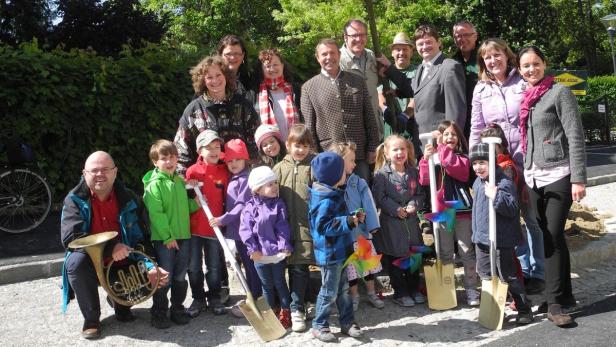 Eine Gruppe von Erwachsenen und Kindern posiert mit Spaten für ein Foto.