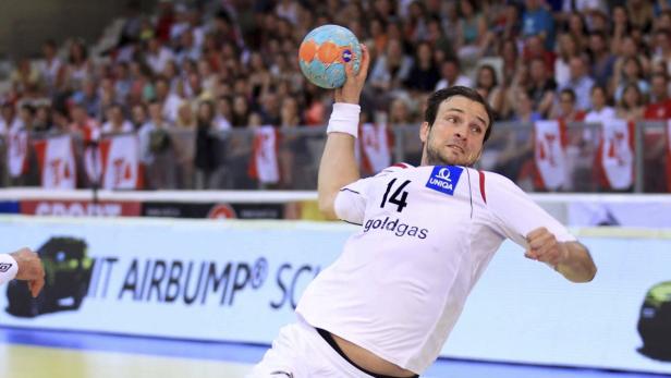 Ein Handballspieler mit der Nummer 14 wirft einen Ball während eines Spiels.