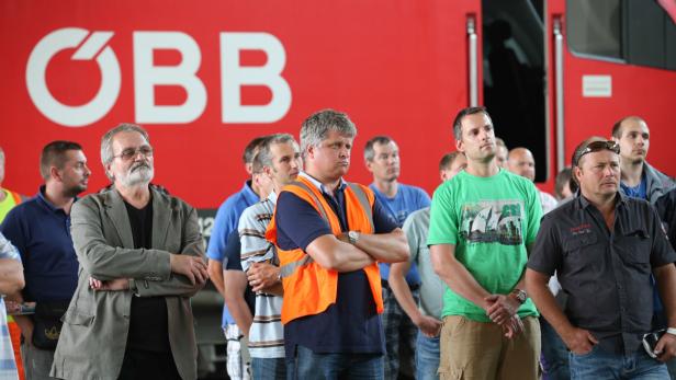 Eine Gruppe von Menschen steht vor einem roten ÖBB-Zug.