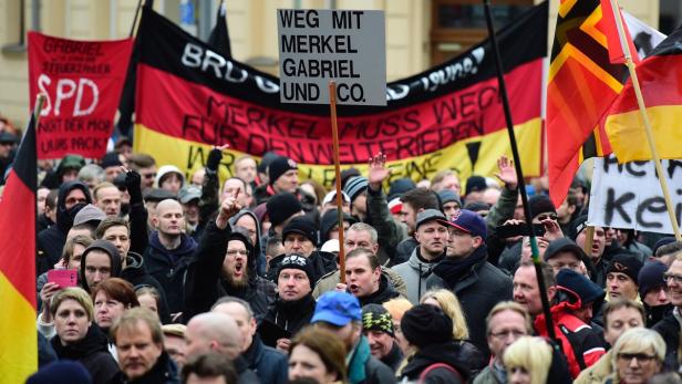 Eine Menschenmenge demonstriert mit Deutschlandflaggen und Schildern gegen Merkel und Gabriel.