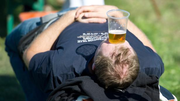 Ein Mann liegt entspannt mit einem Bierbecher auf der Stirn.