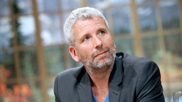 Ein Mann mit grauem Haar und Bart schaut nach oben.