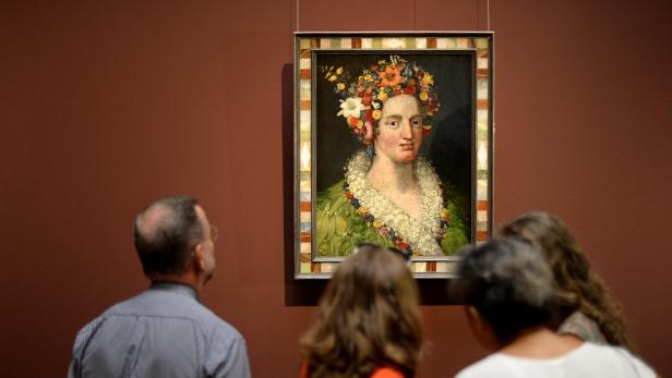 Besucher betrachten ein Porträt einer Frau mit Blumen im Haar in einem Museum.