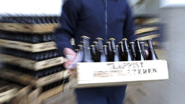 Eine Person trägt eine Kiste voller Bierflaschen.
