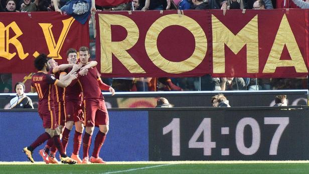 Fußballspieler von AS Rom feiern ein Tor vor einem Banner mit der Aufschrift „Roma“.