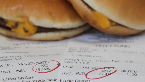 Zwei Cheeseburger liegen auf einer Quittung mit ausgewiesener Mehrwertsteuer.